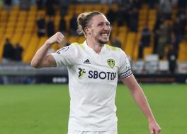 A footballer on a pitch smiling and punching the air
