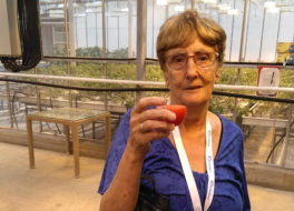 A woman holding up a glass in toast and looking at the camera