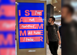 A man standing next to a digital advertisement