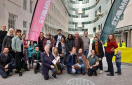 A group of people, some standing and some kneeling, all looking at the camera, some holding a flag