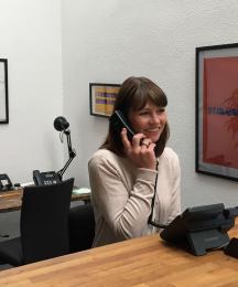 A woman at a desk speaking into a phone