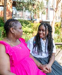 A mother sitting with her daughter on a park bench and chatting