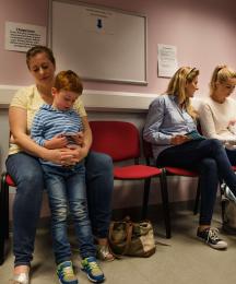 Mothers with children on their laps sitting in a doctor's waiting room