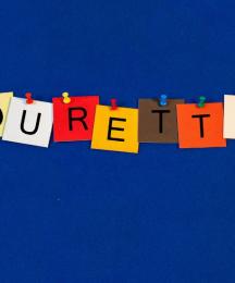 An illustrated washing line, with cards pegged to it, each with a letter, spelling out the word 'Tourette's'