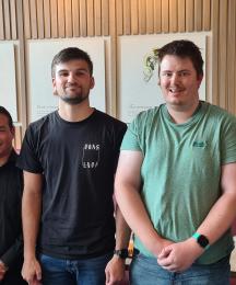 Four men and one woman standing in a line and smiling