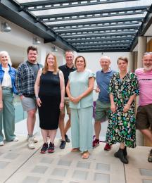 Five men and four women standing together and smiling