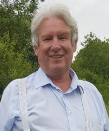 A man in an outdoor setting, smiling