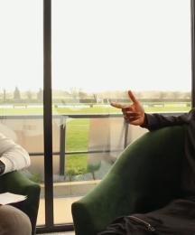 A man interviewing another man, both are seated.