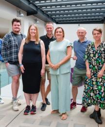 Five men and four women standing together and smiling