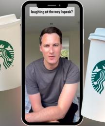 A smartphone displaying a man talking, with two takeaway coffee chain cups