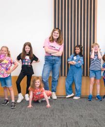 A group of children smiling, with two grown ups 
