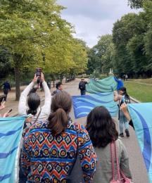 A group of people marching through a park holding flags