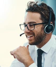 A man in a call centre wearing a phone headset and smiling