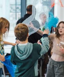 Three children playing with pieces of fabric, waving them through the air