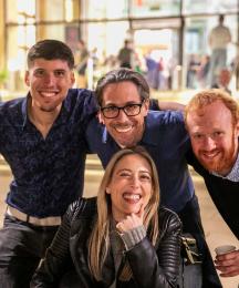 Three men and a woman huddled together and smiling