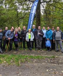 A group of people in an outdoor setting standing beside a banner