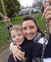 A mother and young son sitting together on a swing