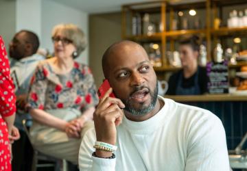A man in a coffee shop talking into a mobile phone