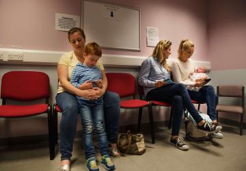 Mothers with children on their laps sitting in a doctor's waiting room