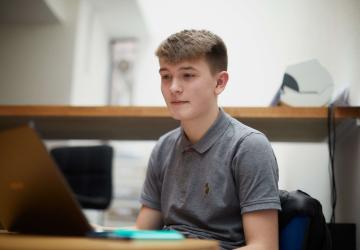 A  young man looking at a laptop computer