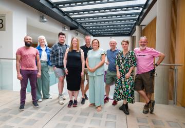 Five men and four women standing together and smiling