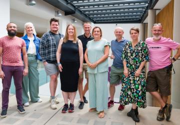 Five men and four women standing together and smiling