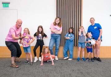 A group of children smiling, with two grown ups 