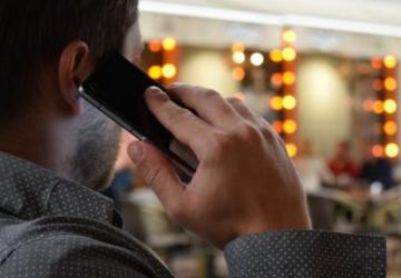 The back of a man's head as he speaks into a mobile phone.