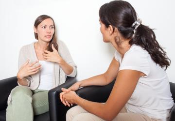Two women sitting and talking, with one gesticulating with her hands