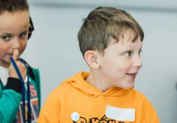 A young boy looking to the right, with another boy behind, looking to the left