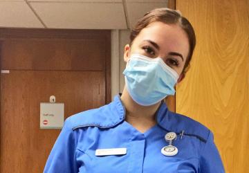 A nurse wearing a facemask looking at the camera