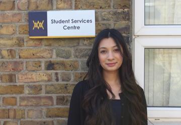 A woman standing in front of a sign saying 'Student Services Centre'