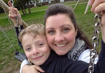 A mother and young son sitting together on a swing