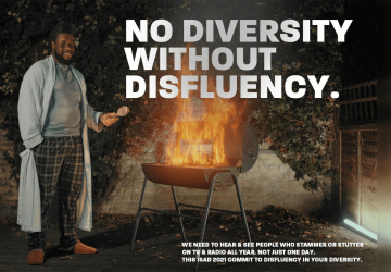 A man standing next to a barbecue that has flames coming out of it.