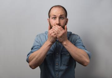 A man covering his mouth with his hands in staged surprise