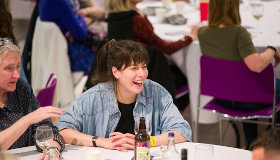 Woman laughing with a group of people at STAMMAFest 2025