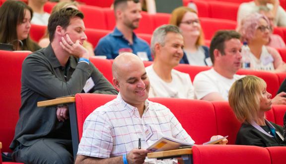 Audience members sitting at a lecture theatre talk at STAMMAFest 2024