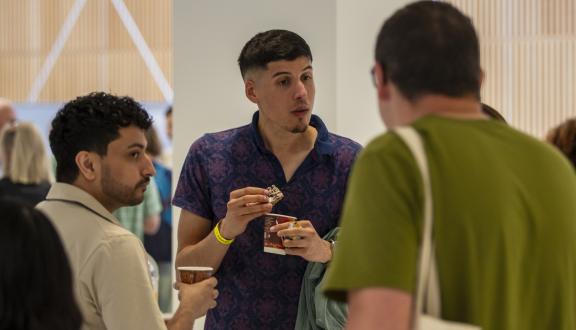 A group of young men standing with drinks inside the conference venue