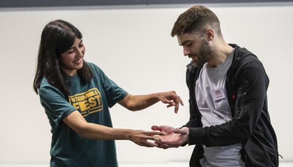 A woman and man smiling and miming on stage at STAMMAFest