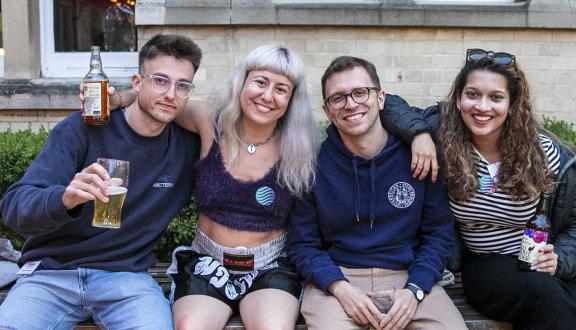 Two young men and two young women with drinks sat outside the conference venue