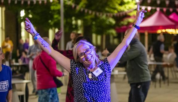 A woman smiling with arms raised outside the conference venue