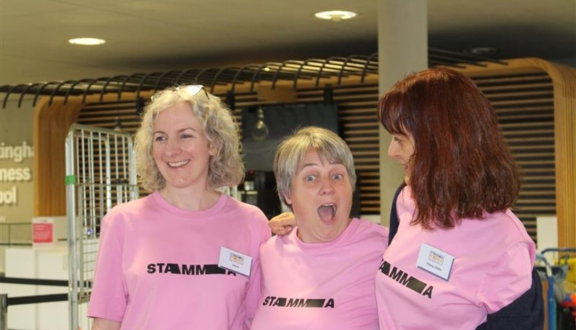 STAMMA conference staff Clara, Kirsten and Hilary smiling and huddled inside
