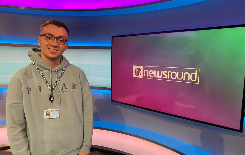 Landing my dream career in TV A man standing in a TV studio next to a television screen, looking at the camera