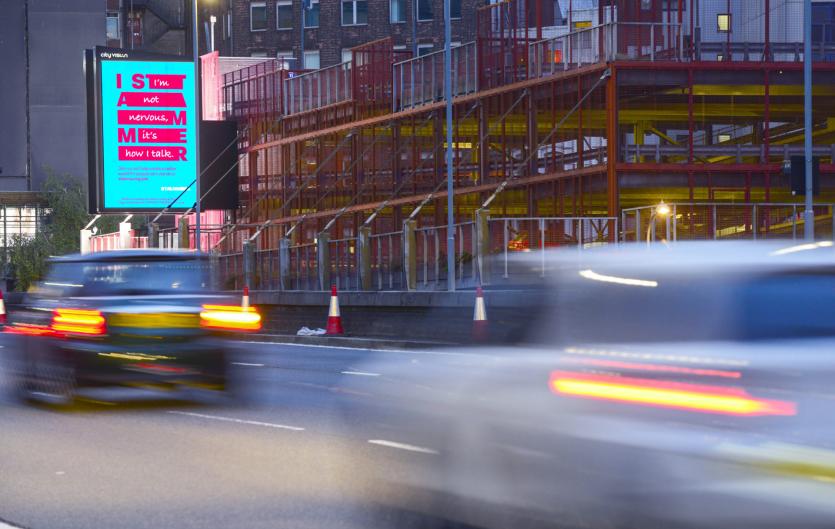 A busy road with an outdoor advertisement displaying the I Stammer campaign