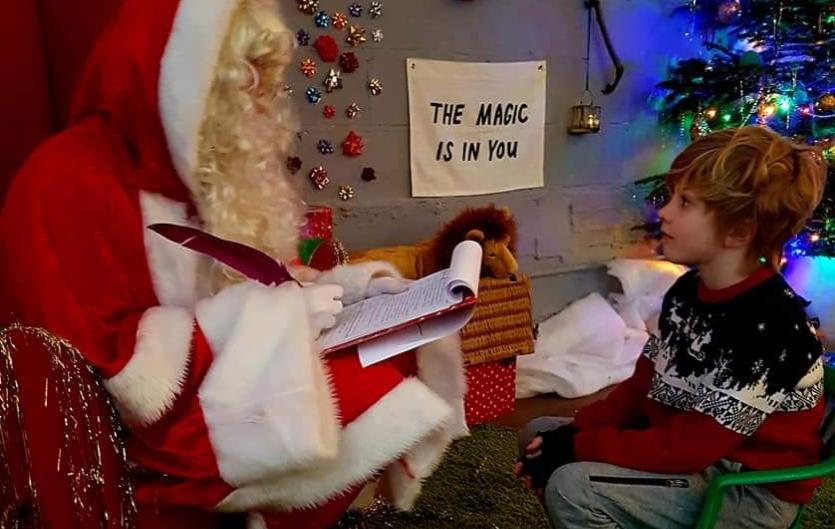 Boy with a department store Santa Claus. Sign saying: 'The magic is in you.'