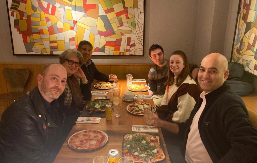 North London Stammer Support Group Six people sitting at a restaurant table looking at the camera and smiling.