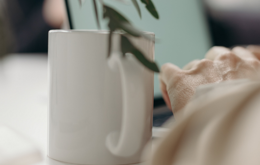 Diary of a (not so) new helpline/webchat volunteer An arm with a mug next to it, beside a laptop and a houseplant
