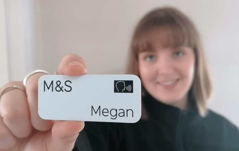 A woman holding a name badge up to the camera 