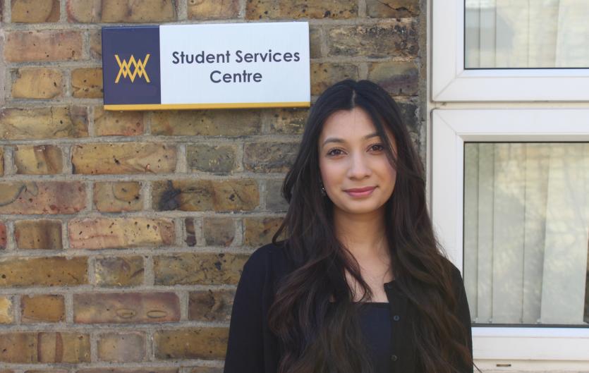 College A young woman standing beside a sign saying 'Student services centre'