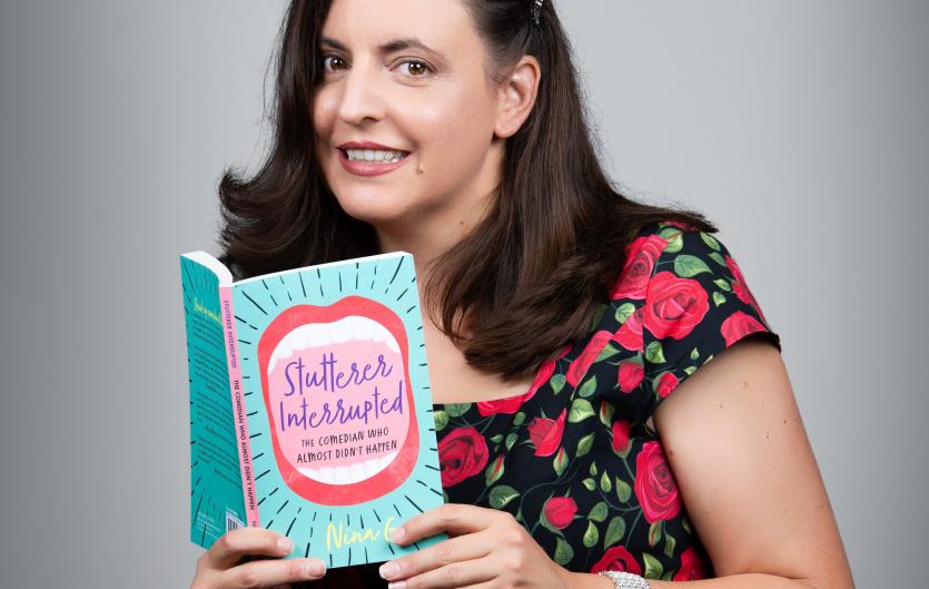 Stutterer Interrupted Nina G displaying a copy of her book
